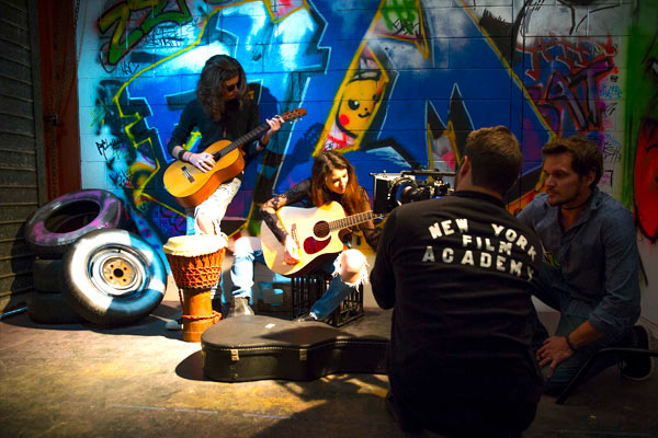 NYFA Students filming a scene with many instruments in front of a graffitied wall